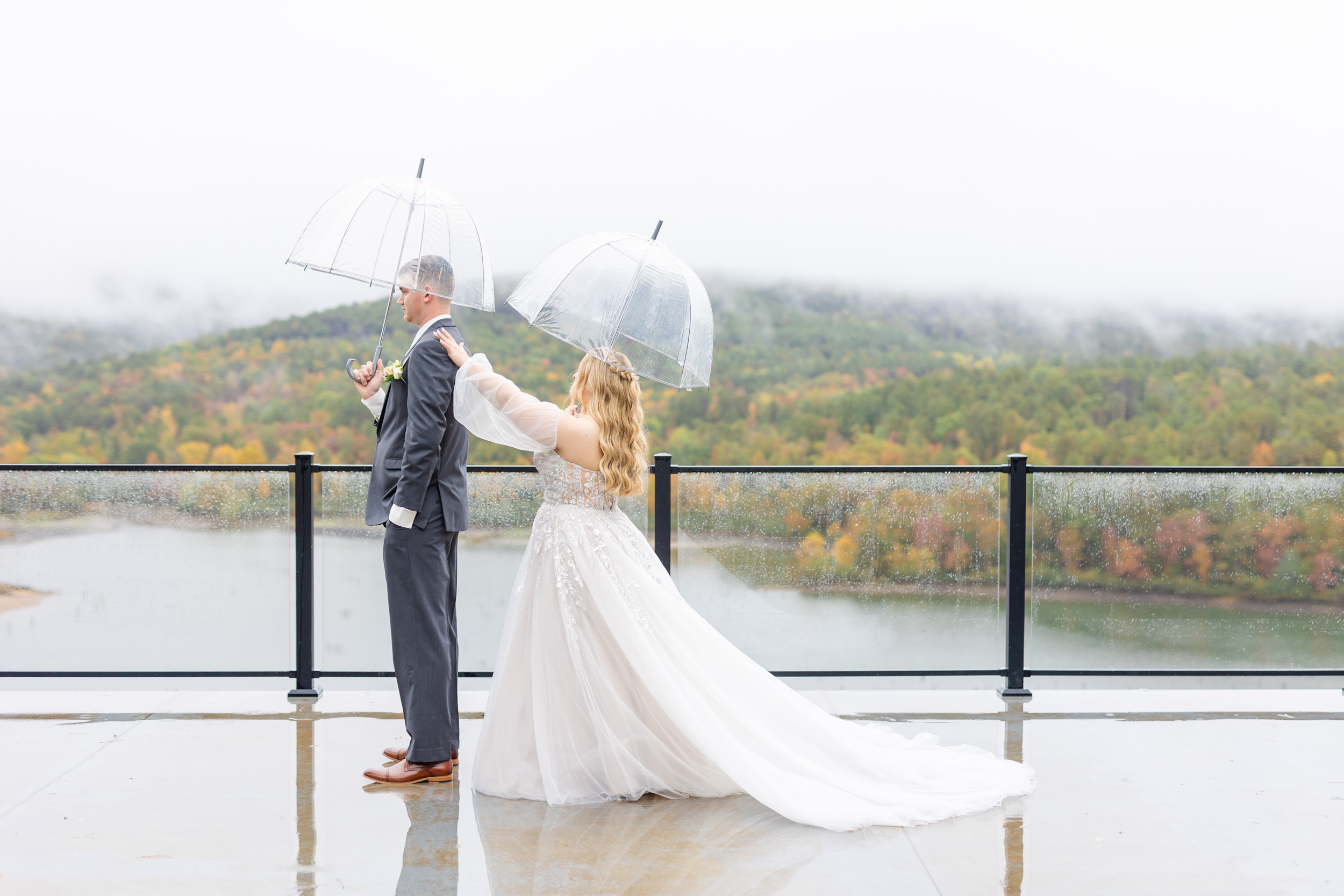 first look with clear umbrellas, the bride tapping the groom on his shoulder
