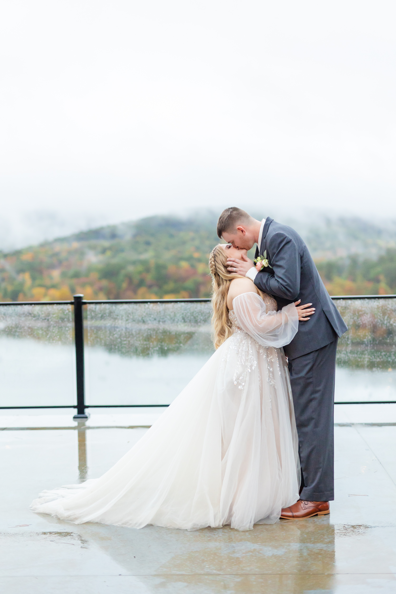 groom kissing his bride with the lake view in the background